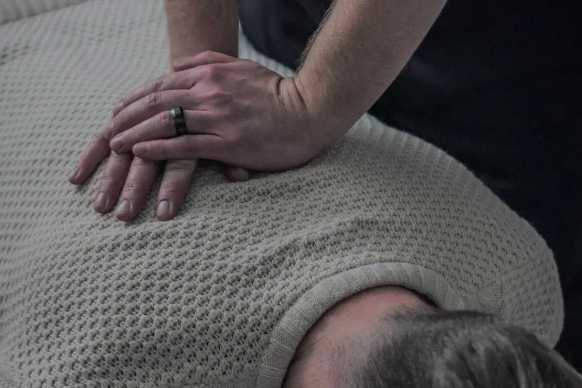 Las manos de un fisioterapeuta trabajando sobre la espalda de un paciente.